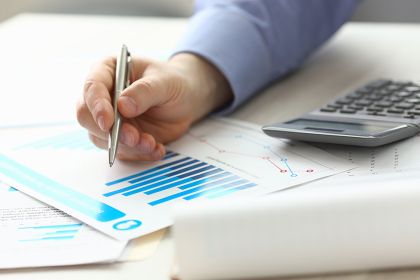 Foto: Person zeigt mit Stift auf Akten